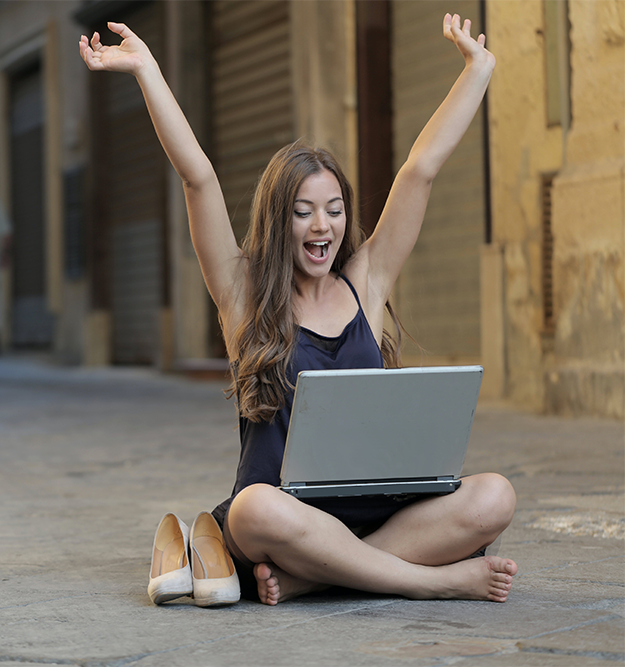 happy woman with laptop sat in the street